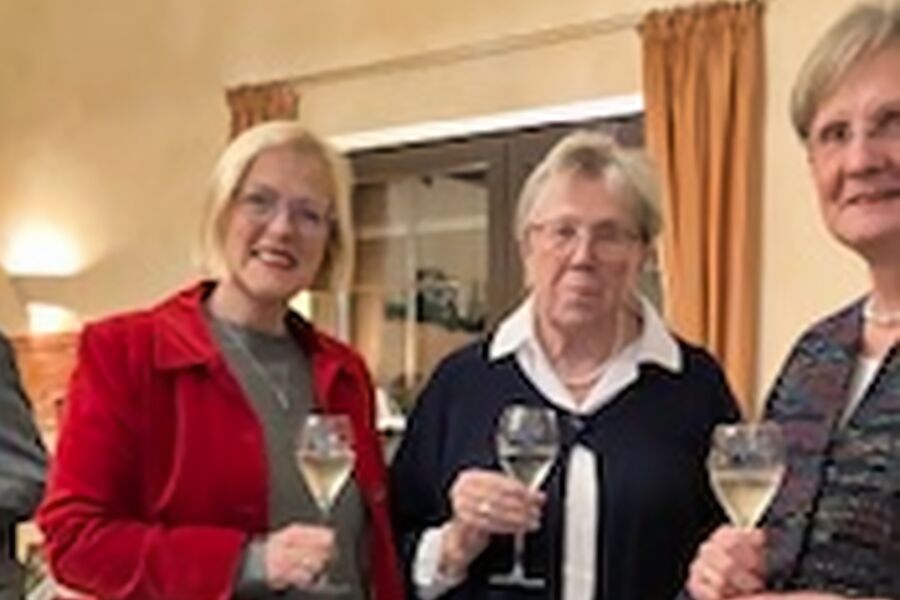 Drei Frauen mit Sektglas lächeln in die Kamera