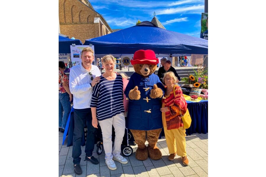 Lionsmitglieder mit Paddington Bär vor Lionsstand