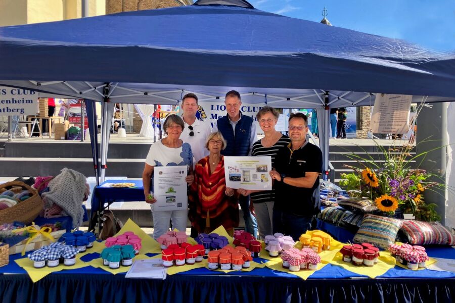 Lionsmitglieder am Stand mit Spendenurkunden