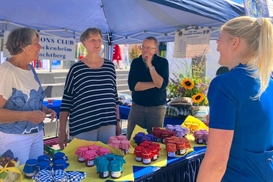 Personen vor und hinter dem Lionsstand mit Konfituren und im Hintergrund Strickwaren