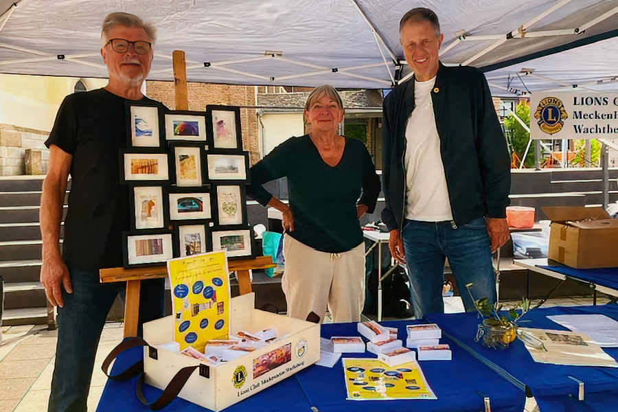 Drei Personen am Benefizstand vor dem Angebot "Kunst to go"