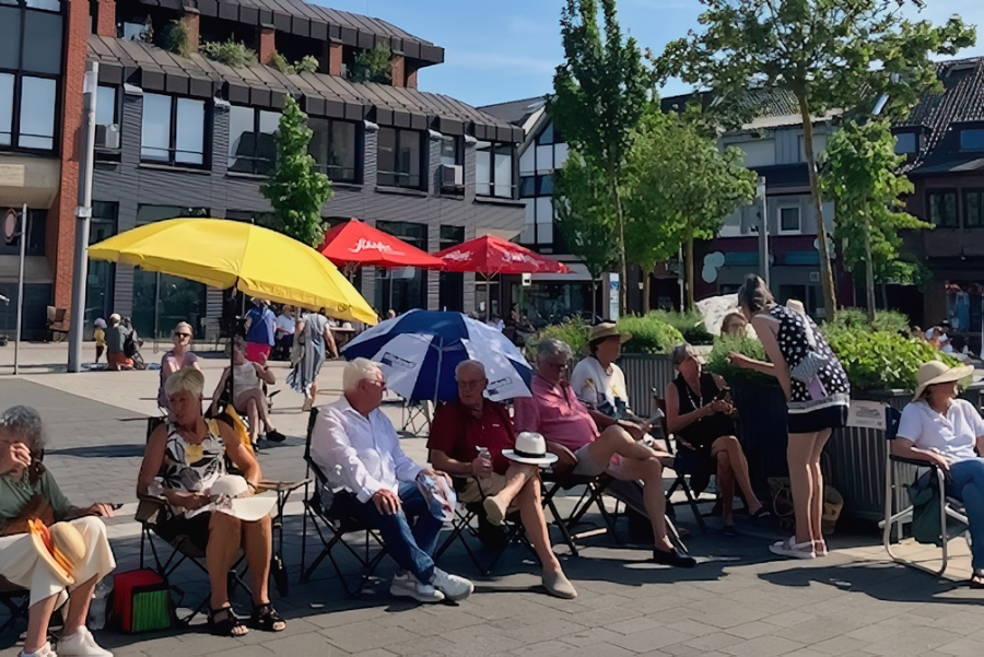 Publikum unter Sonnenschirmen auf mitgebrachten Klappstühlen