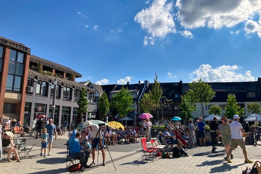Zuschauer auf Klappstüheln und mit Sonnenschirmen